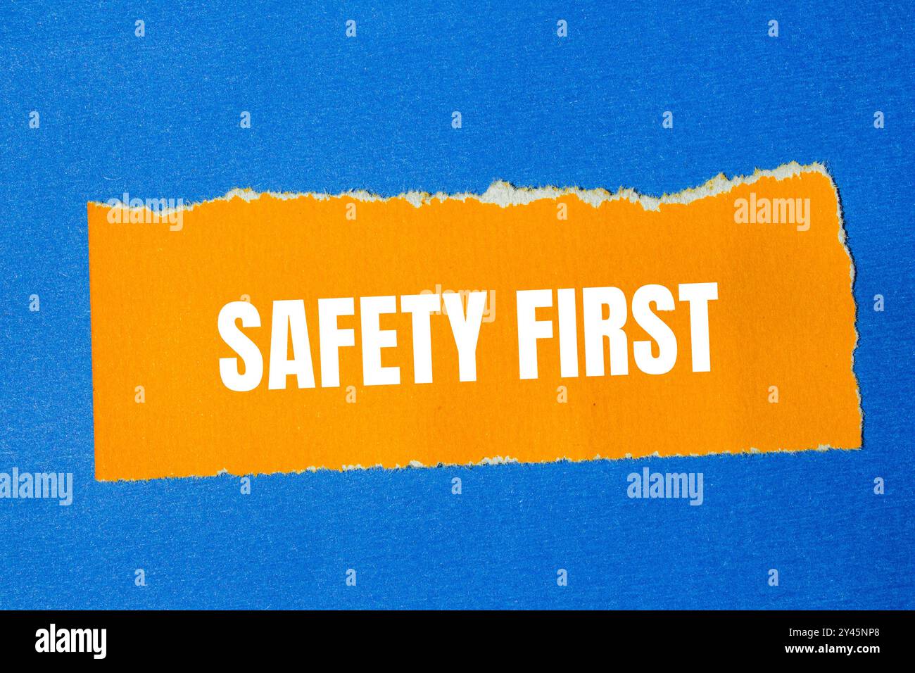 Safety First-Meldung auf gerissenem orangefarbenen Papier mit blauem Hintergrund. Symbol für konzeptionelle Sicherheit an erster Stelle. Kopierbereich. Stockfoto