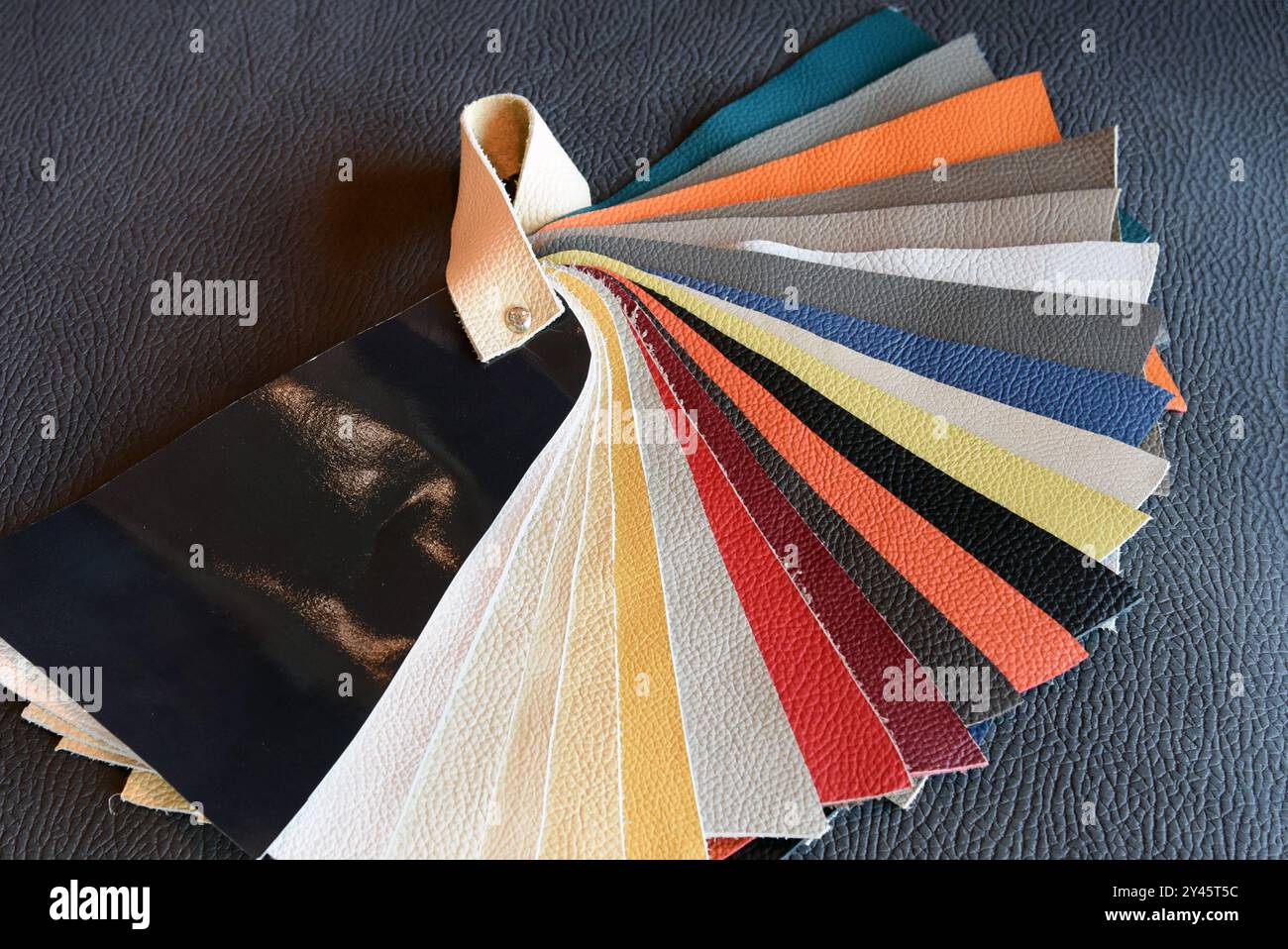Farbtabelle aus Leder mit Mustern für die Inneneinrichtung, die auf einer schwarzen Ledercouch liegen Stockfoto