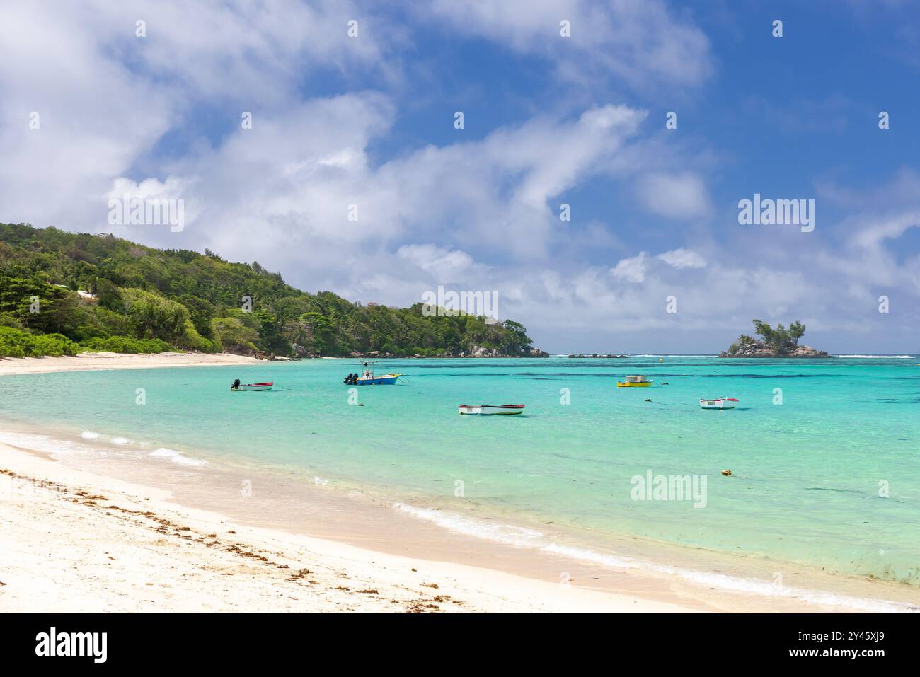 Anse Royale Strandlandschaft, Seychellen. Blick auf die Küste mit kleinen Motorbooten unter blauem Himmel mit weißen Wolken an einem sonnigen Tag Stockfoto