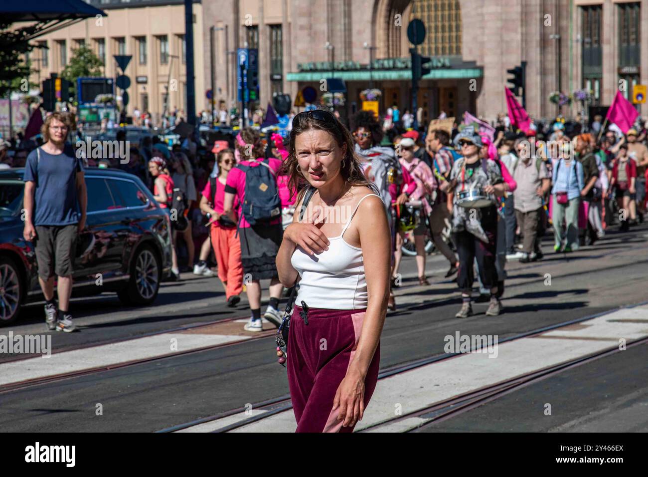 Eine Frau, die verwirrt mit den Demonstranten des Aussterbens der Rebellion Finnland im Hintergrund in Helsinki, Finnland, aussieht Stockfoto
