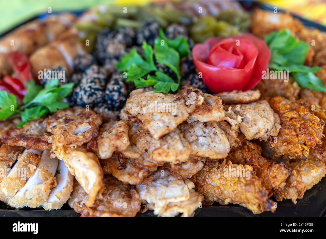 Eine lebendige Platte mit verschiedenen gegrillten und frittierten Fleischsorten, garniert mit frischem Gemüse und Kräutern Stockfoto