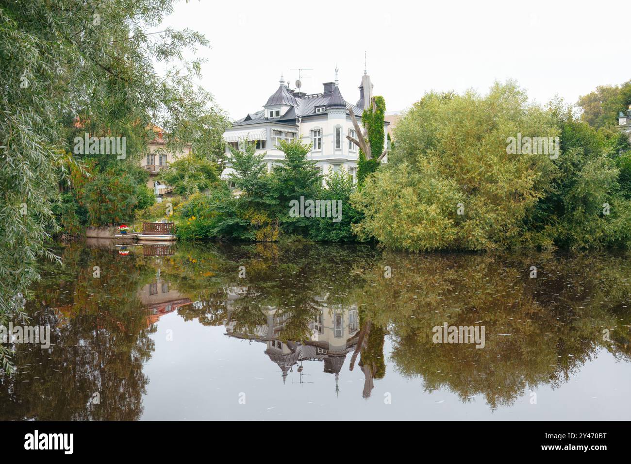 Üppiges Grün und Villa am Flussufer im Stadtpark mit hohen Bäumen und Reflexionen im Fluss Svartån. Entspannung und urbanes Entspannungskonzept. Orebro, Swed Stockfoto