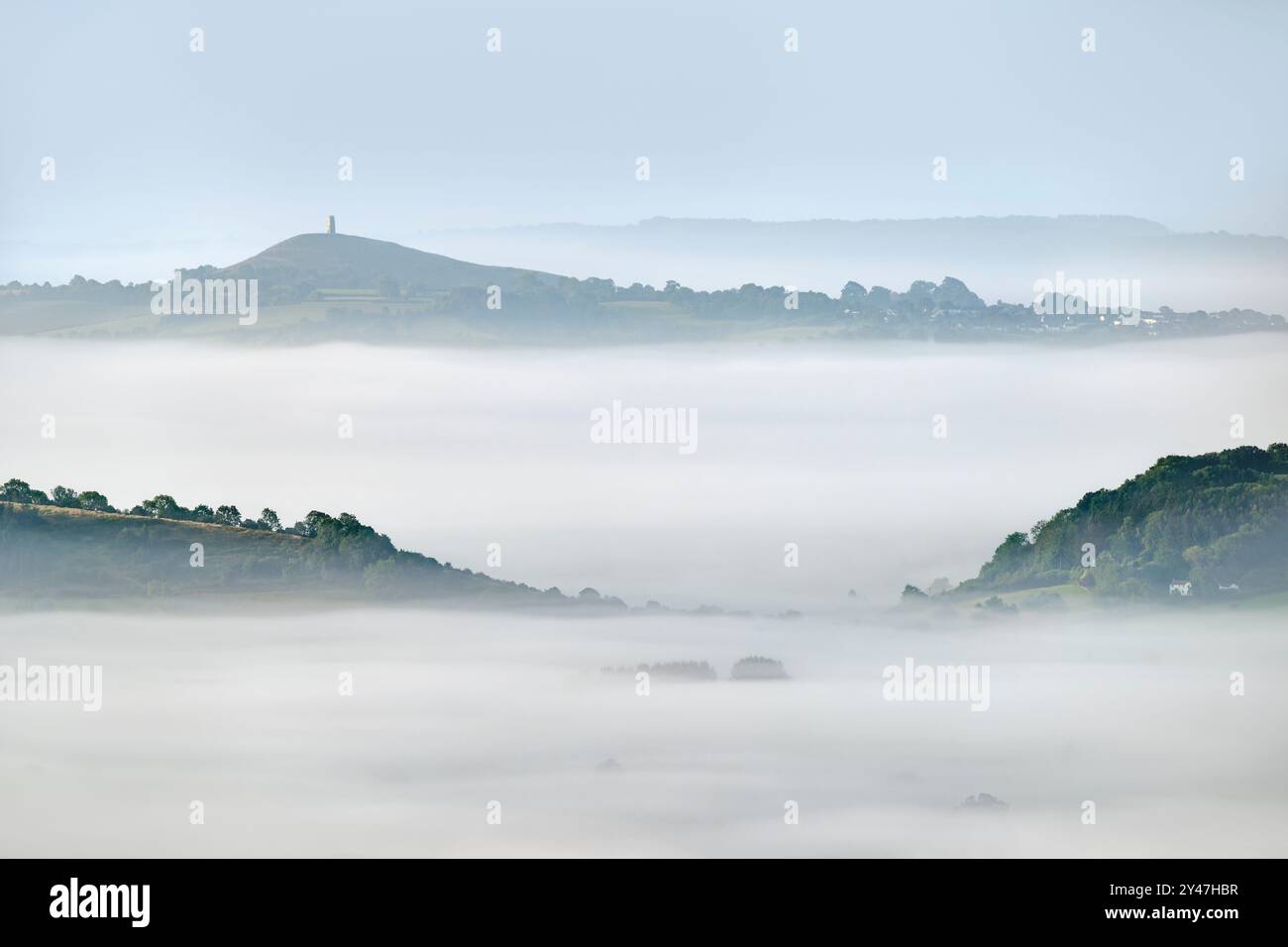 Starker Morgennebel auf den Somerset Levels, von den Mendip Hills, Somerset, Großbritannien, mit Bäumen, die gerade erst durchbrechen, und Glastonbury bis nach Stockfoto