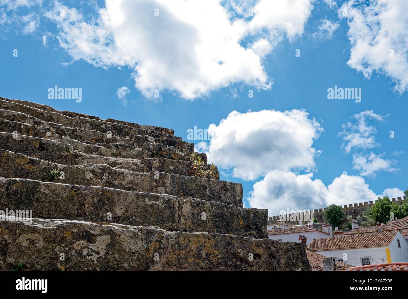 Antike Steintreppen, die zu den mittelalterlichen Mauern von Óbidos unter einem hellblauen Himmel führen Stockfoto