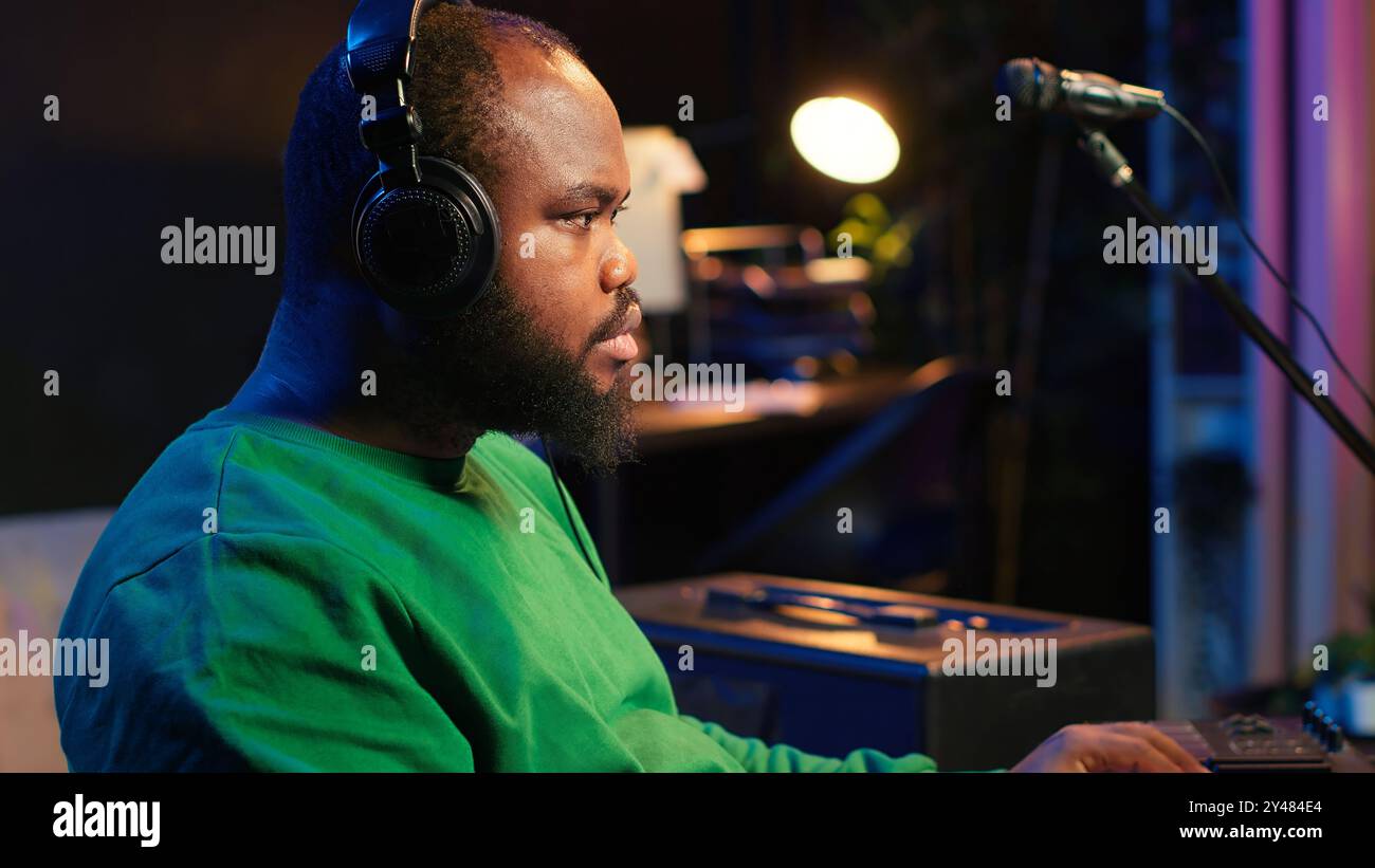 Music Composer spielt elektronische Klaviertasten und nimmt neue Titel auf, um Audioaufnahmen zu erstellen, bevor Musik gestartet wird. Der Produzent verwendet Synthesizer, Postproduktion. Kamera A.. Stockfoto