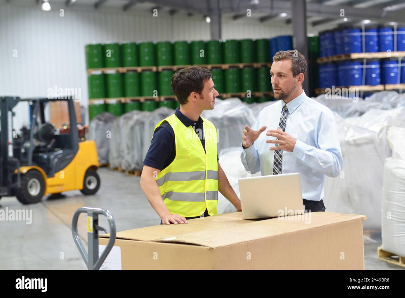 Treffen der Manager und Mitarbeiter im Lager - Gabelstapler und Innenraum der industriellen Gebäude Stockfoto