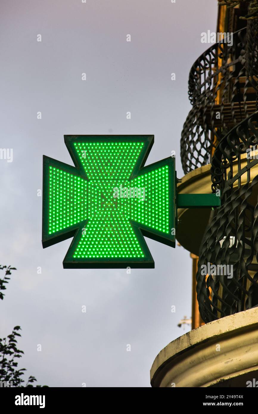 Beleuchtetes grünes Apotheken-Kreuzschild mit LED-Lichtern. Barcelona, Katalonien, Spanien. Stockfoto