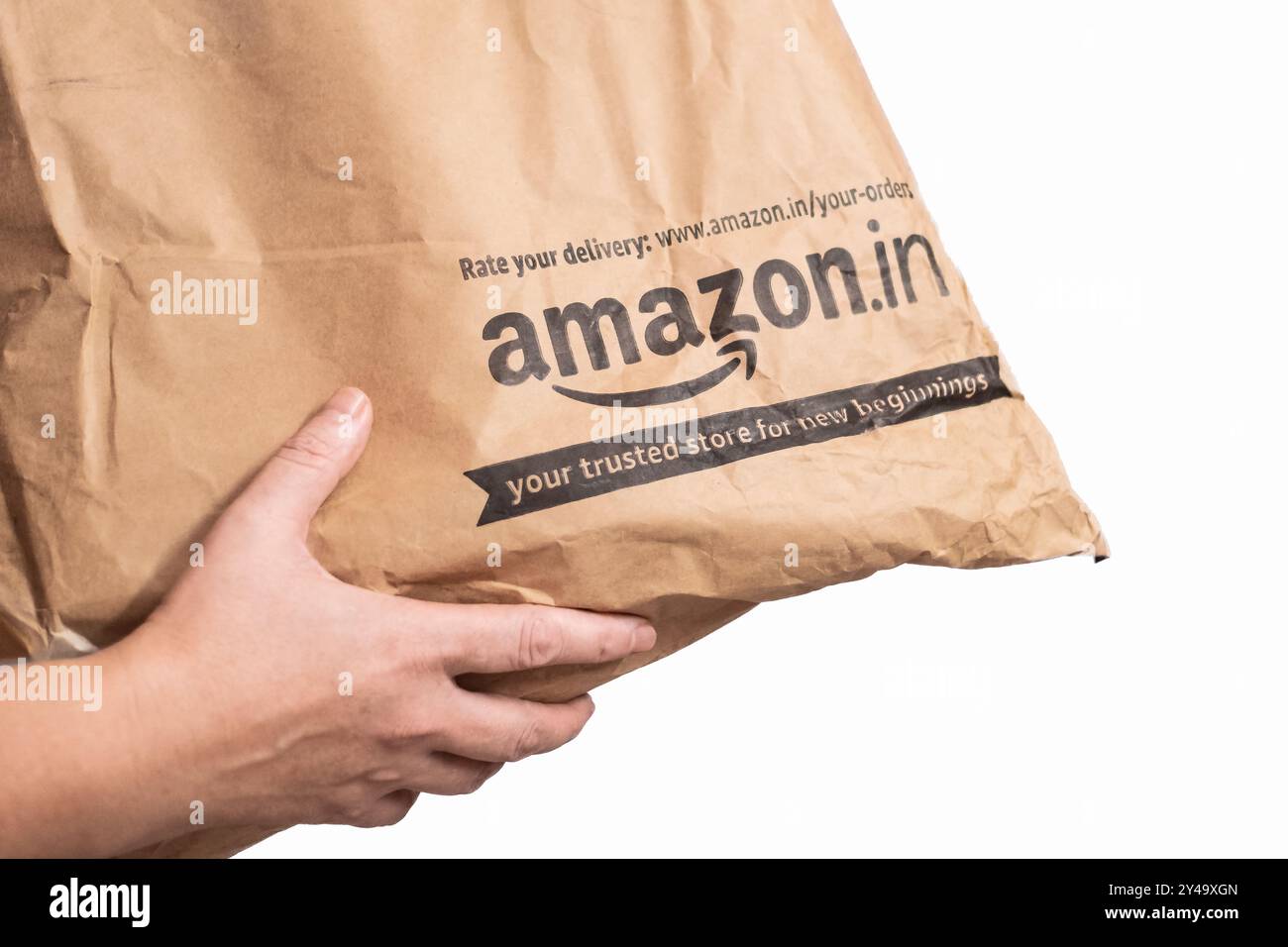 Paketpaket mit Eigenlieferung von Amazon Indien. Amazon.in Etikett Verpackungsbeutel isoliert auf weißem Hintergrund. Weibliche Hände erhalten einen Amazon bo Stockfoto