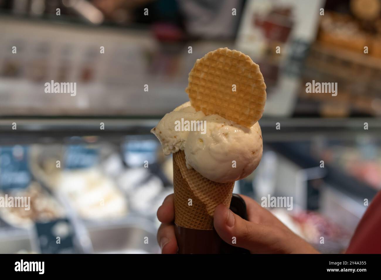Hand hält Schokoladeneiskegel nahe oben isoliert. Stockfoto