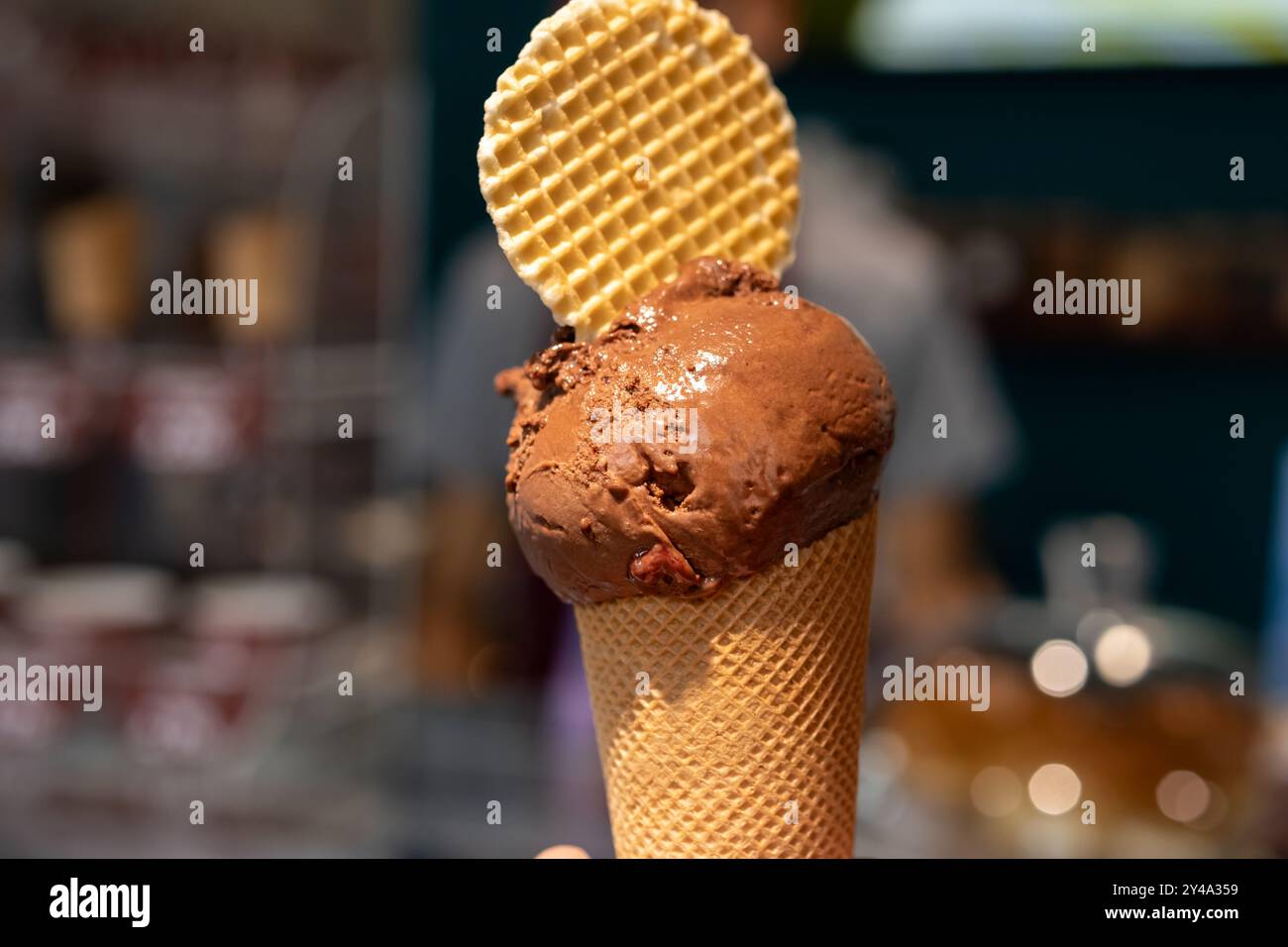 Hand hält Schokoladeneiskegel nahe oben isoliert. Stockfoto