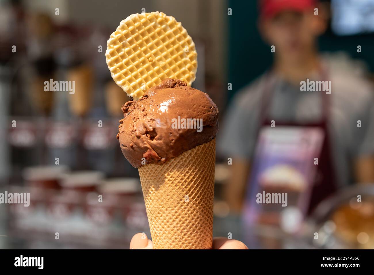 Hand hält Schokoladeneiskegel nahe oben isoliert. Stockfoto