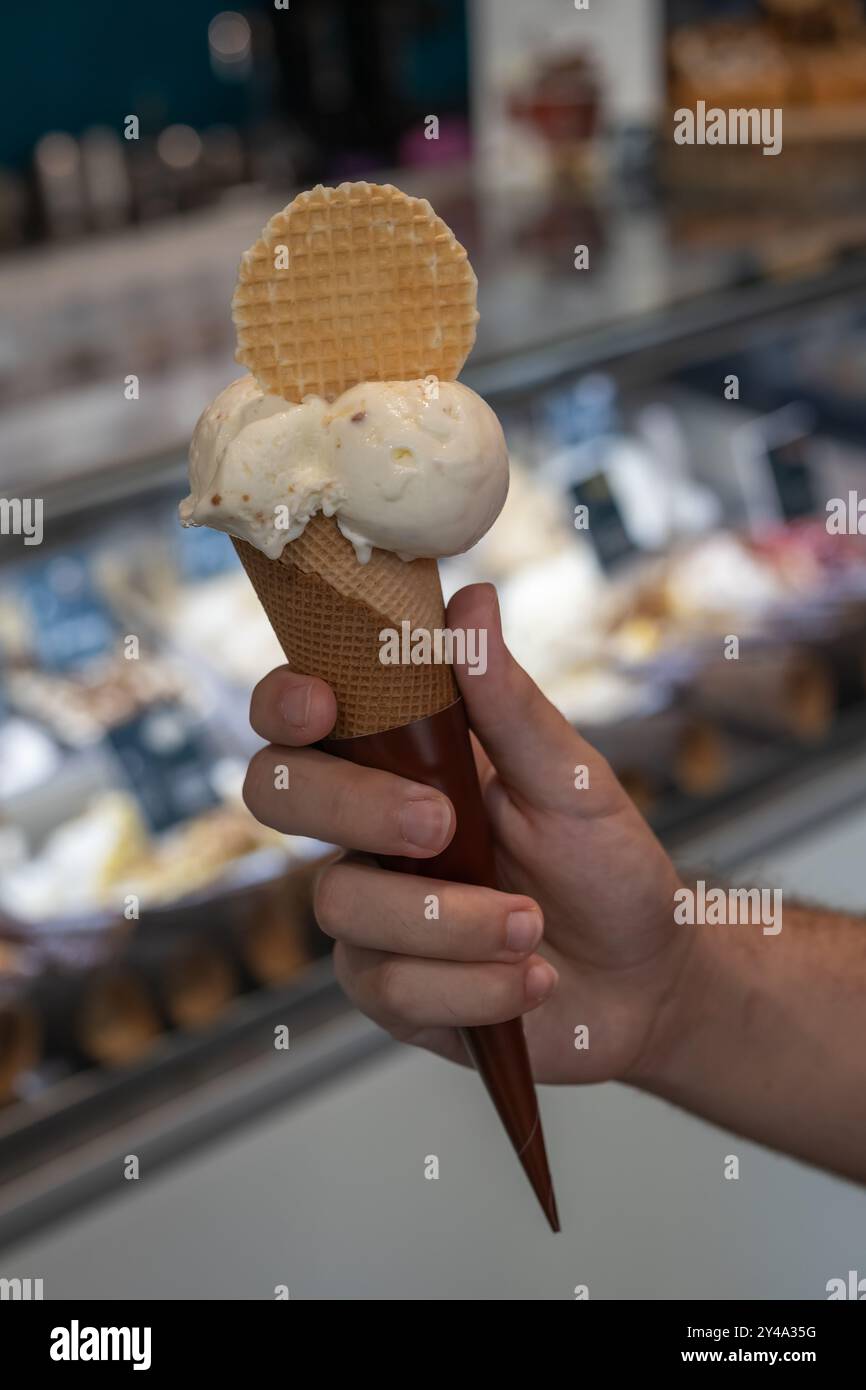 Hand hält Schokoladeneiskegel nahe oben isoliert. Stockfoto