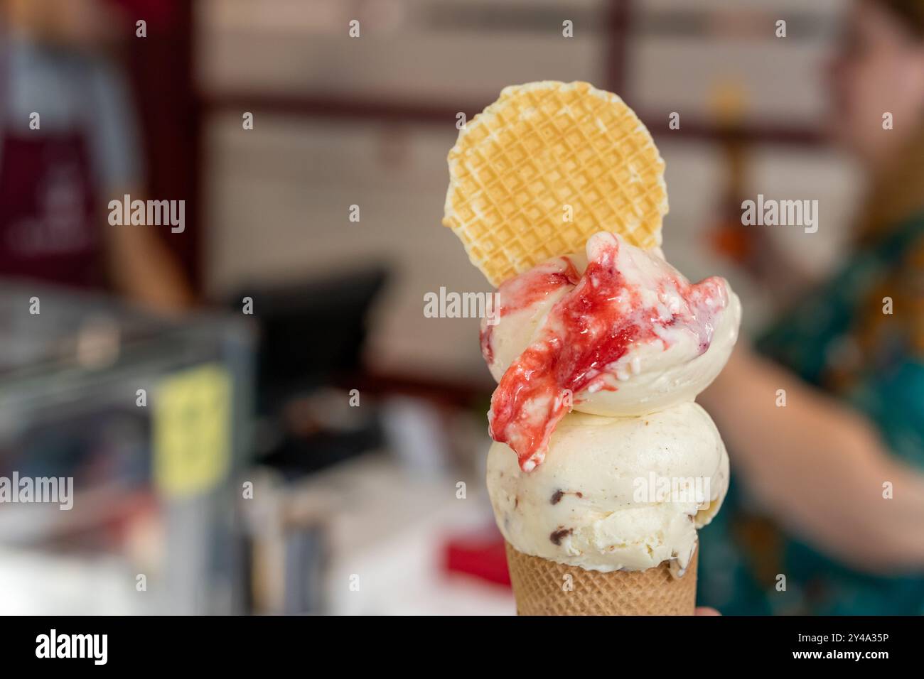 Hand hält Schokoladeneiskegel nahe oben isoliert. Stockfoto