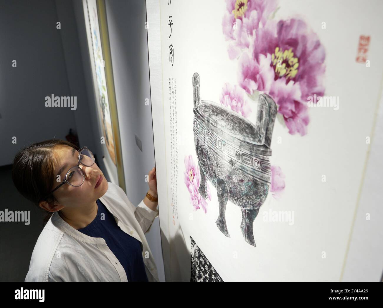 (240917) -- LUOYANG, 17. September 2024 (Xinhua) -- Qian Xiayu beobachtet ein Kunstwerk von Jinshi Bogu Malerei im Luoyang Huaxia Reibkultur Museum in Luoyang, Zentralchinas Provinz Henan, 11. September 2024. Jinshi Bogu, ein immaterielles Kulturerbe von Luoyang, bezieht sich auf das auf dem Papier geschaffene Gemälde, das bereits mit farbigen Zeichen und Mustern markiert ist, die mit Reibungstechniken gemacht wurden. Die Kombination der Charaktere und Muster, die zunächst auf Steinen oder antiken Artefakten eingraviert wurden, mit den handgemalten Bildern und der Kalligrafie eines Künstlers stellt die Integration des di dar Stockfoto