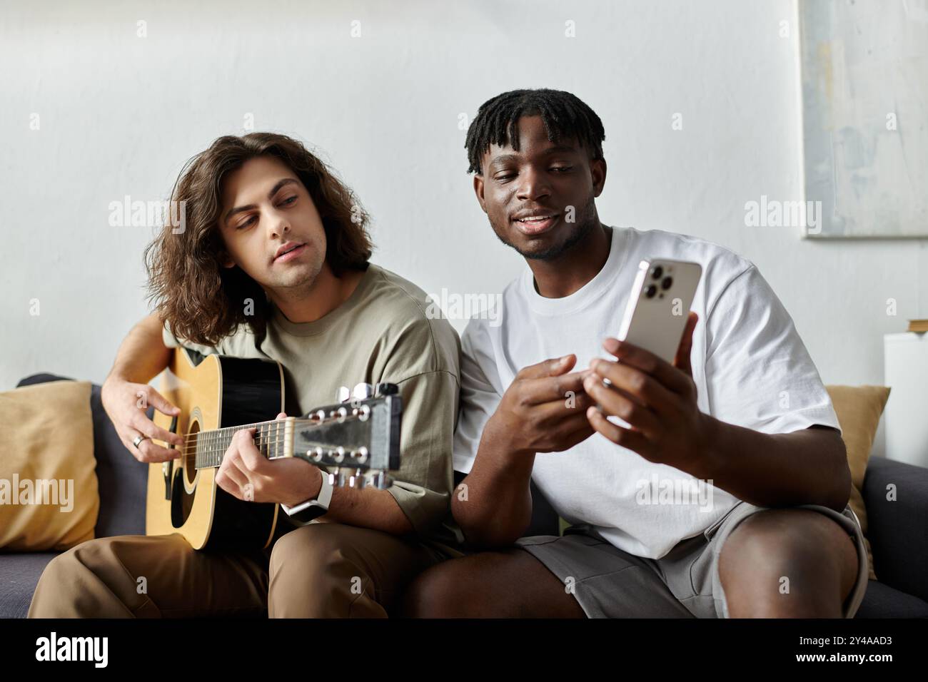 Zwei Partner genießen einen gemütlichen Moment zusammen, wobei einer Gitarre spielt und der andere ein Lächeln teilt. Stockfoto