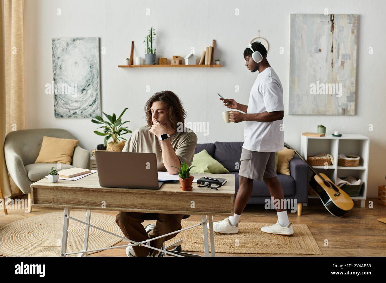 Zwei Partner verbringen einen warmen Moment zu Hause, einer konzentriert sich auf die Arbeit, der andere in Musik. Stockfoto