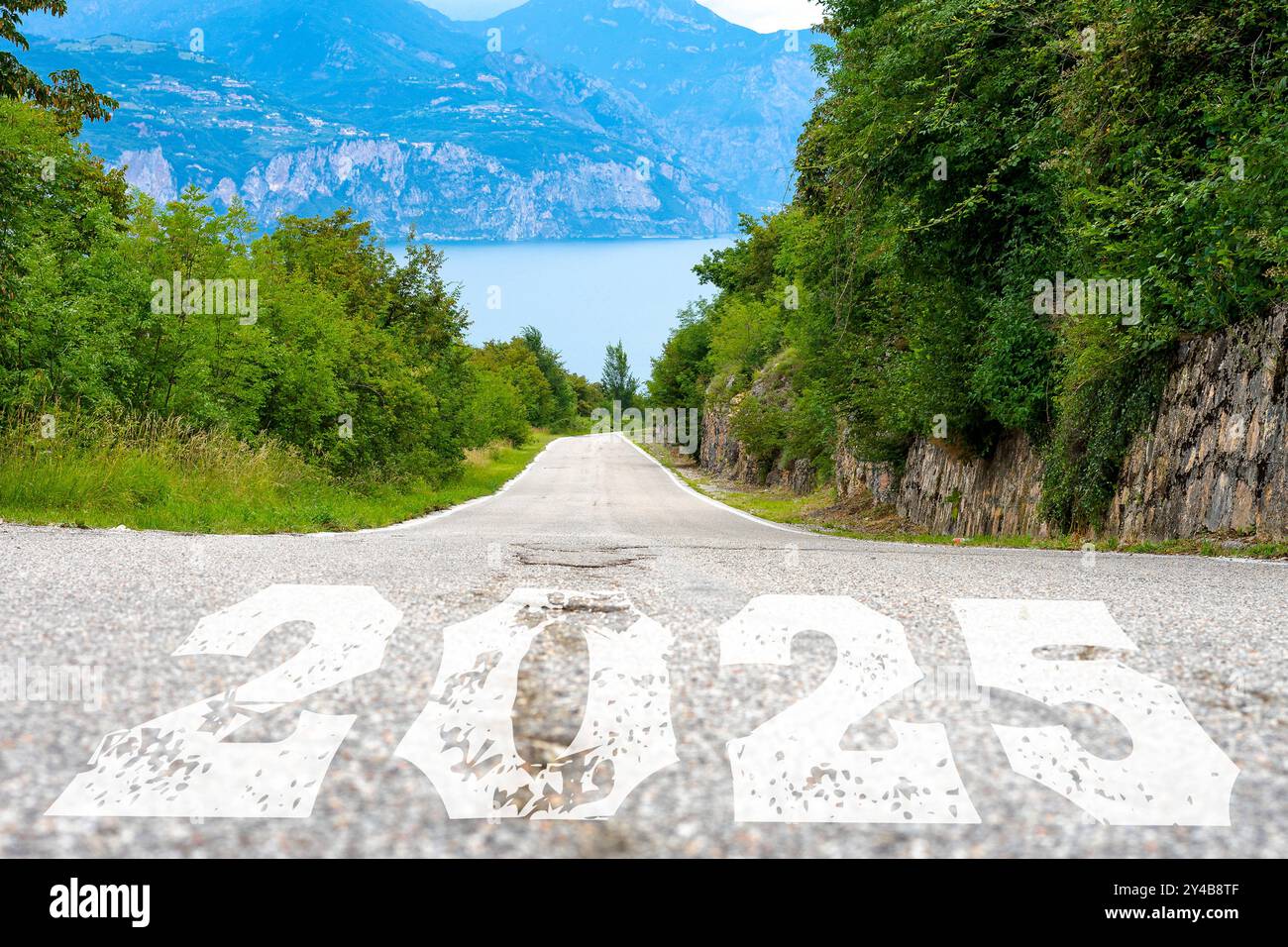 16. September 2024: Eine leere Straße führt in die Ferne, umgeben von grünen Bäumen und Bergen. Das Jahr 2025 ist auf dem Asphalt gemalt und symbolisiert die Straße ins kommende Jahr. FOTOMONTAGE *** eine leere Straße führt in die Ferne, umgeben von grünen Bäumen und Bergen. Auf dem Asphalt ist die Jahreszahl 2025 aufgemalt, was symbolisch den Weg in das kommende Jahr darstellt. FOTOMONTAGE Stockfoto