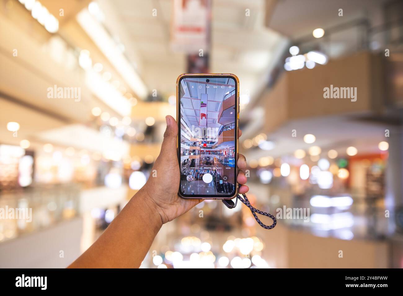 Ein Mann, der einen Supermarkt mit Smartphone fotografiert. Der Mann wird mit seinem Handy gesehen, um Fotos von Objekten um ihn herum zu machen Stockfoto