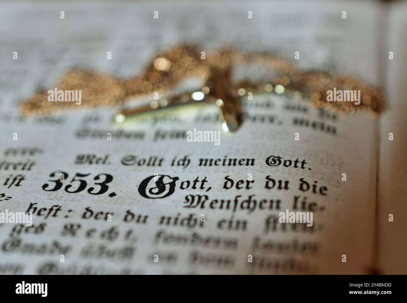 Goldenes Kreuz und Kette auf einem alten deutschen Psalmbuch Stockfoto