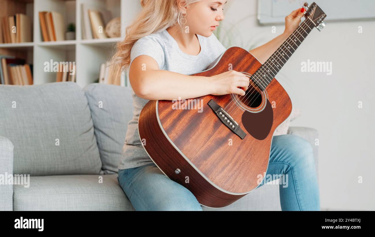 Gitarrenspieler. Inspirierte Frau. Lieblings-Hobby. Nachdenkliche Dame, die Saiten von Musikinstrumenten spielt, Sitzsofa in hellem Raum. Stockfoto