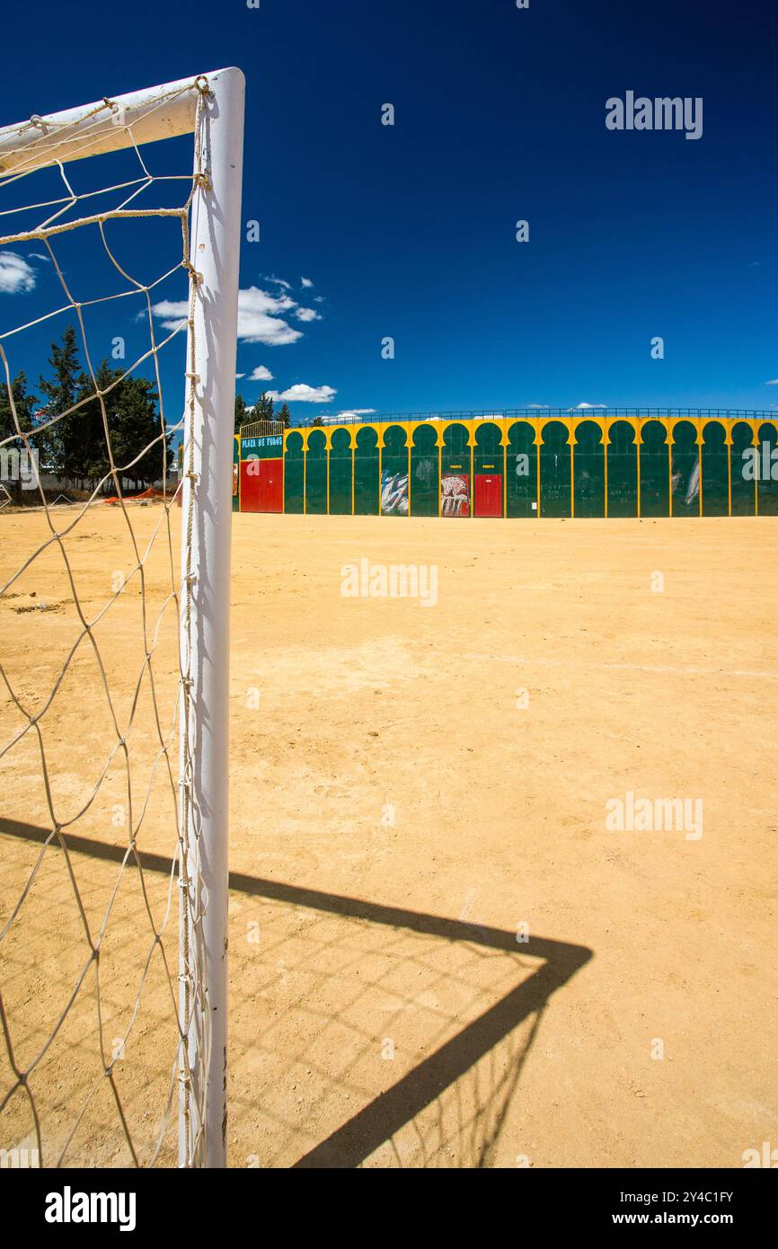 Ein einzigartiger Blick auf eine tragbare Stierkampfarena in Aznalcazar, Sevilla, Spanien, mit einem Fußballtor im Vordergrund unter einem klaren blauen Himmel. Stockfoto