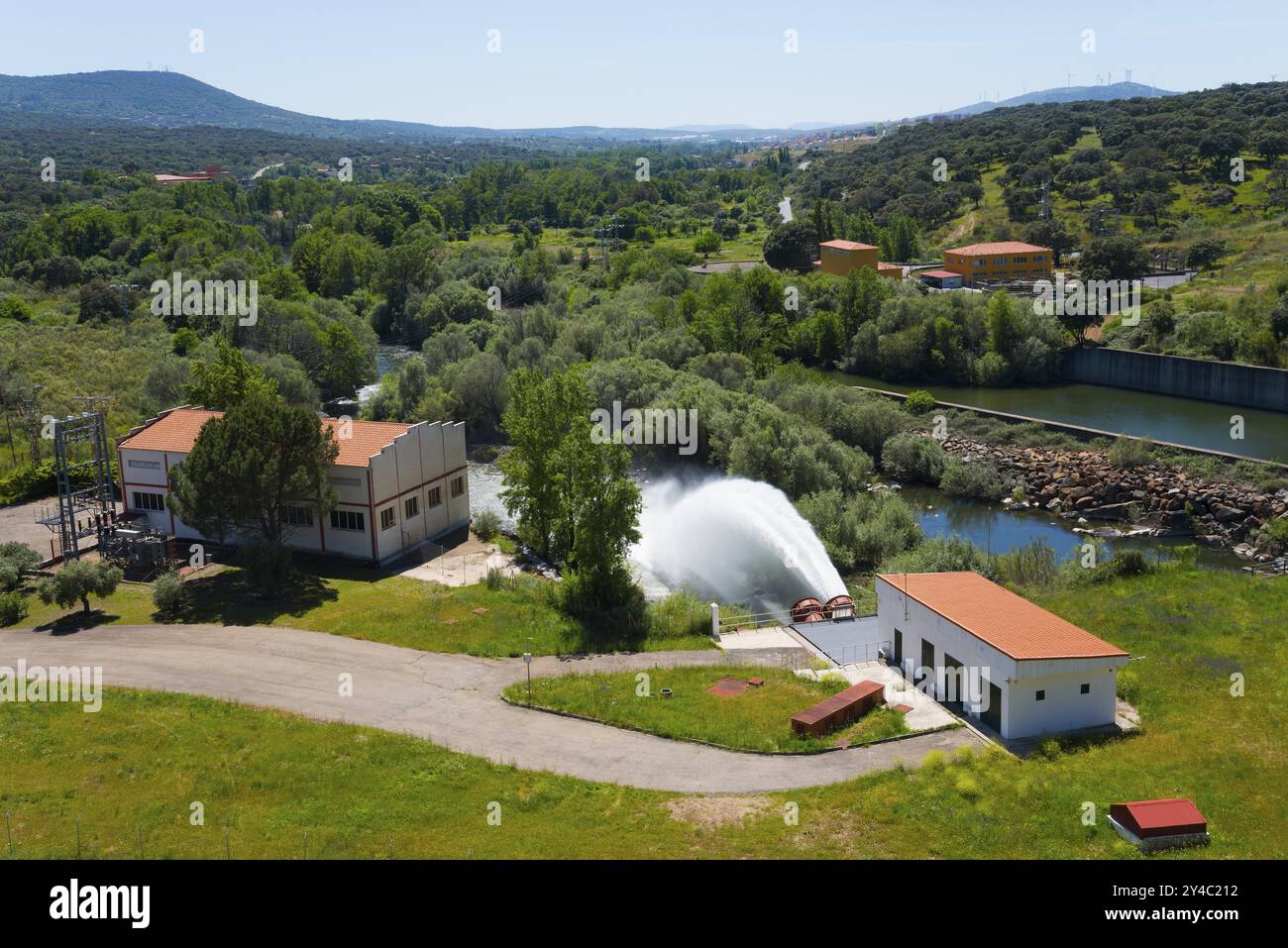 Gebäude in grüner Umgebung mit einem großen Wasserstrom, der aus einem Stausee fließt, Embalse de Plasencia Stausee, Embalse de Jerte, Rio Jerte, Plase Stockfoto