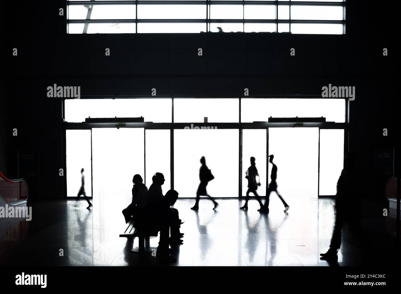 Silhouettenfiguren in der modernen Lobby des Bahnhofs Maria Zambrano in Malaga, Spanien. Die Szene fängt eine Mischung aus Reisen, Archi ein Stockfoto