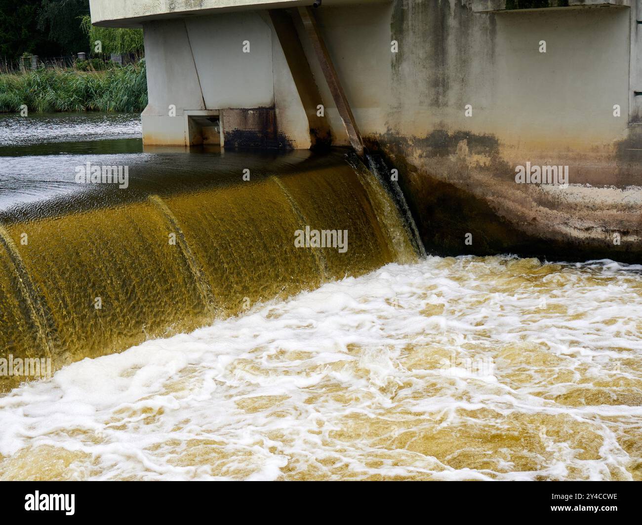 Wasser im Fluss, das durch ein Wehr fließt. Stockfoto