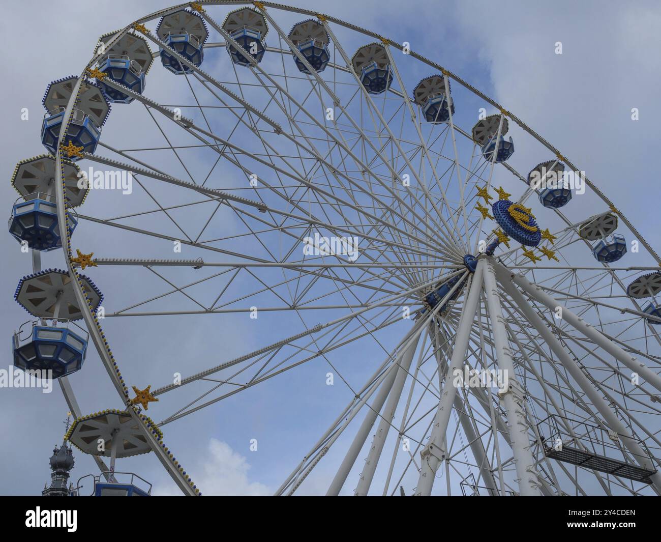 Ein großes Riesenrad mit blauen, weißen und gelben Gondeln vor einem bewölkten Himmel, nijmegen, niederlande Stockfoto