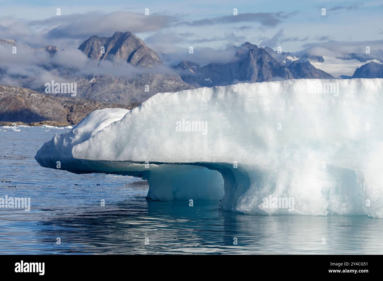 Nahaufnahme eines schmelzenden Eisbergs vor einer beeindruckenden Bergkulisse. Ammassalik Fjord, Ostgrönland, Dänemark Stockfoto