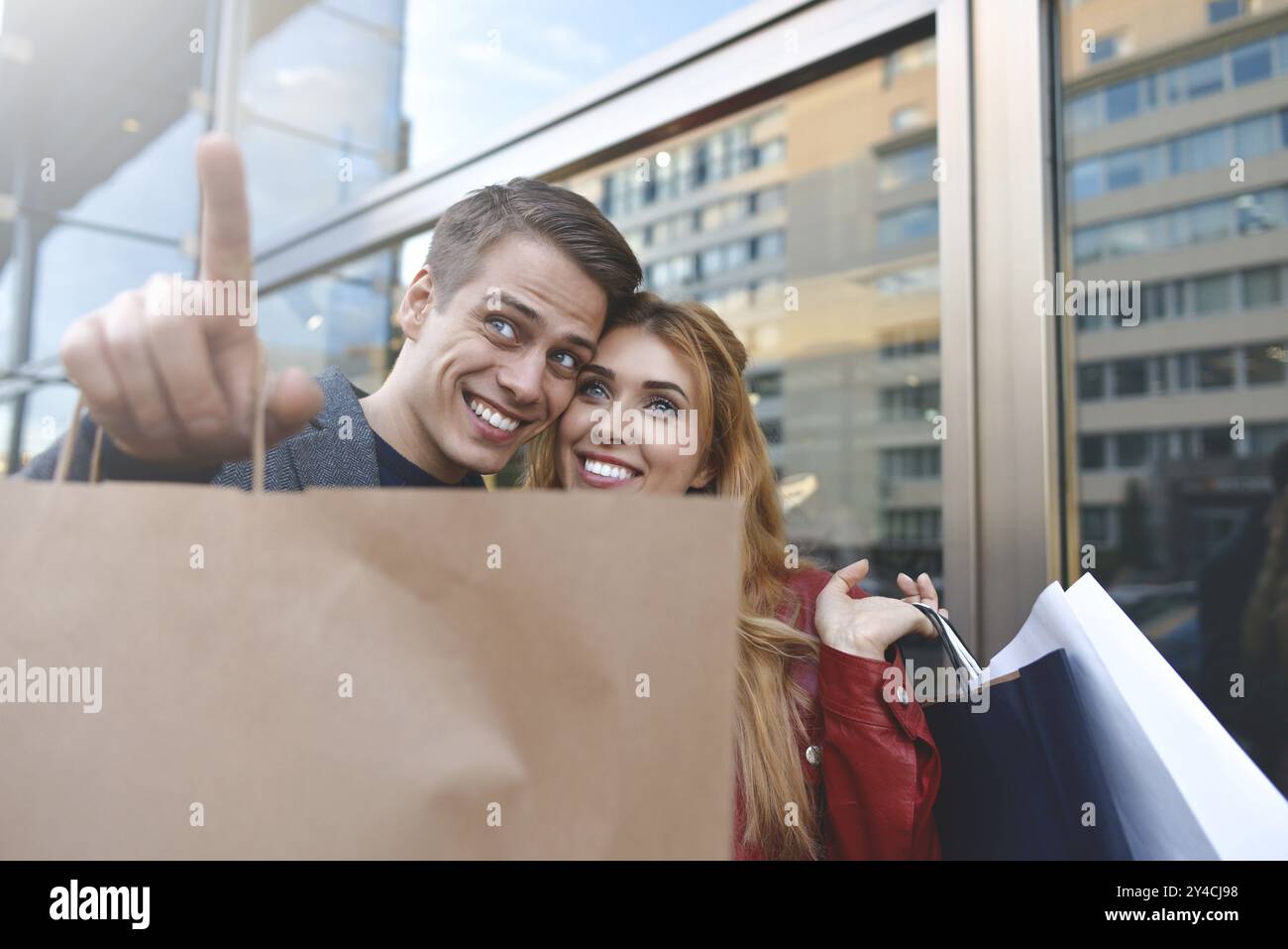 Schönes Paar mit Einkaufstaschen ist reden und lächeln beim Einkaufen in der Mall konzentrieren sich auf die Frau. Heiße Rabatte Stockfoto