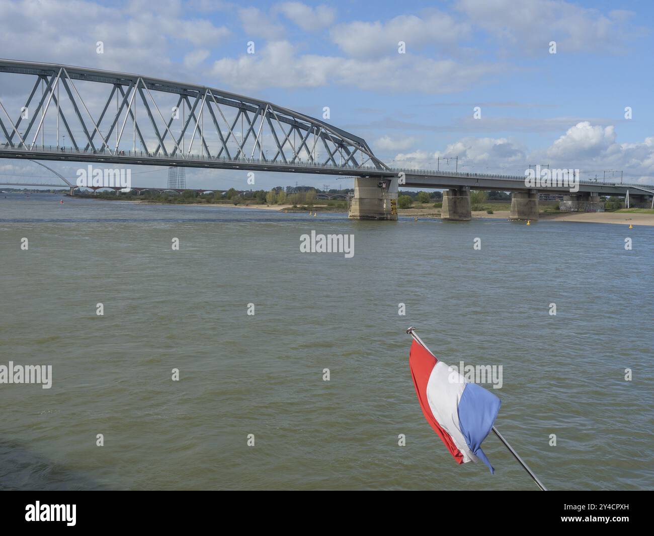 Brücke über den Fluss mit schwingenden Flussflaggen, unter bewölktem Himmel, nijmegen, niederlande Stockfoto