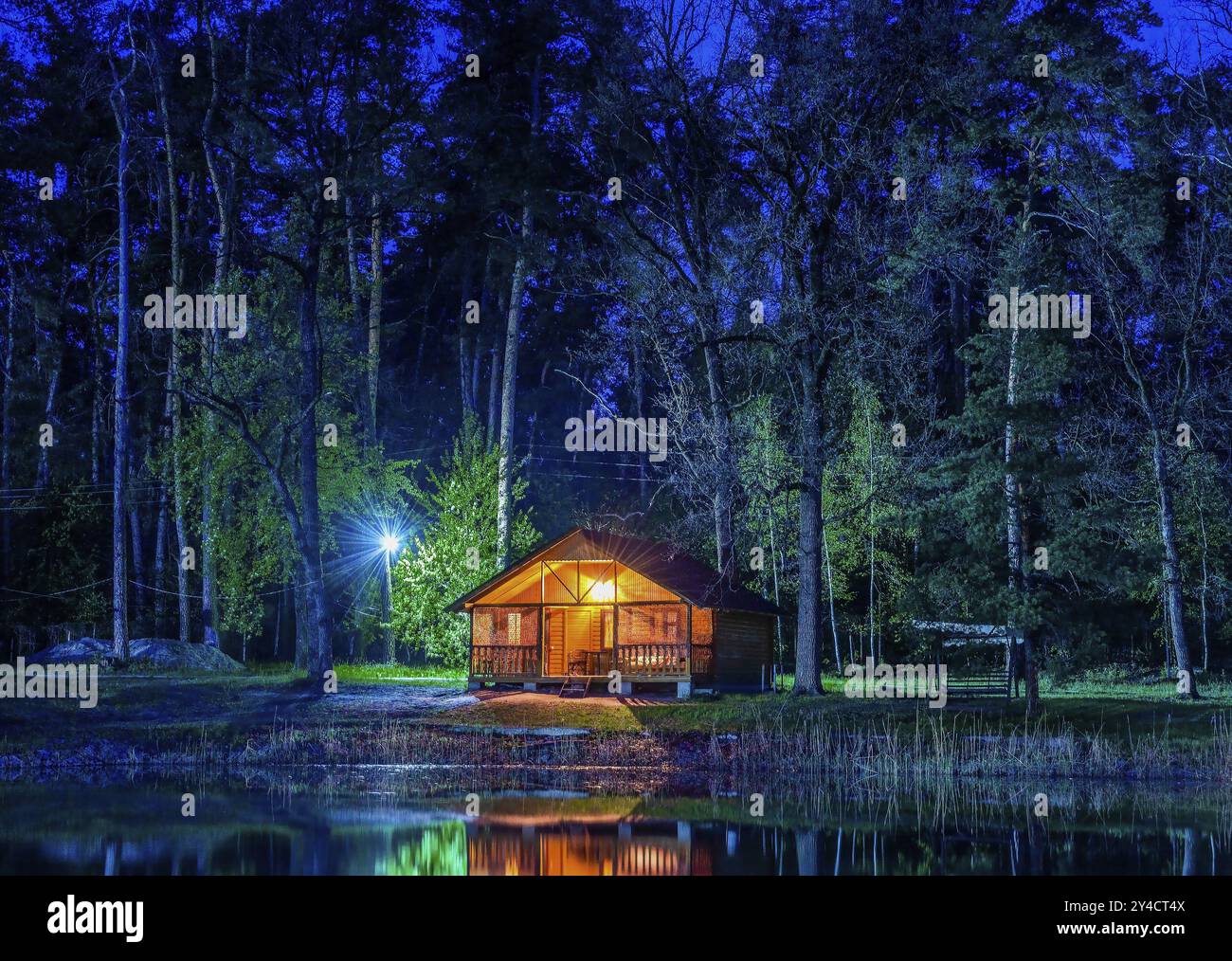 Holz- Haus in conifurous Wald in der Nähe von Teich bei Nacht Stockfoto