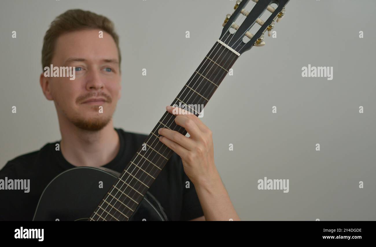 Ein Mann, der Gitarre spielt. Hände auf die Saiten. Nahaufnahme Porträt. Sehnenauswahl. Musiker, der elektrische Gitarre spielt. Bannerhintergrund mit Kopierraum Stockfoto