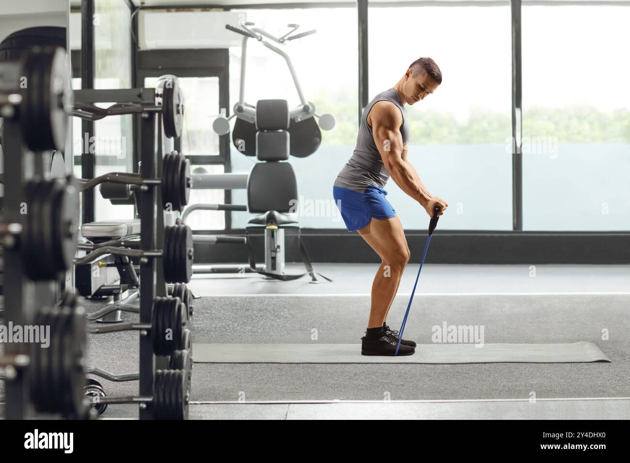 Profilaufnahme eines fitten Mannes, der in einem Fitnessstudio mit einem Widerstandsband auf einer Matte trainiert Stockfoto
