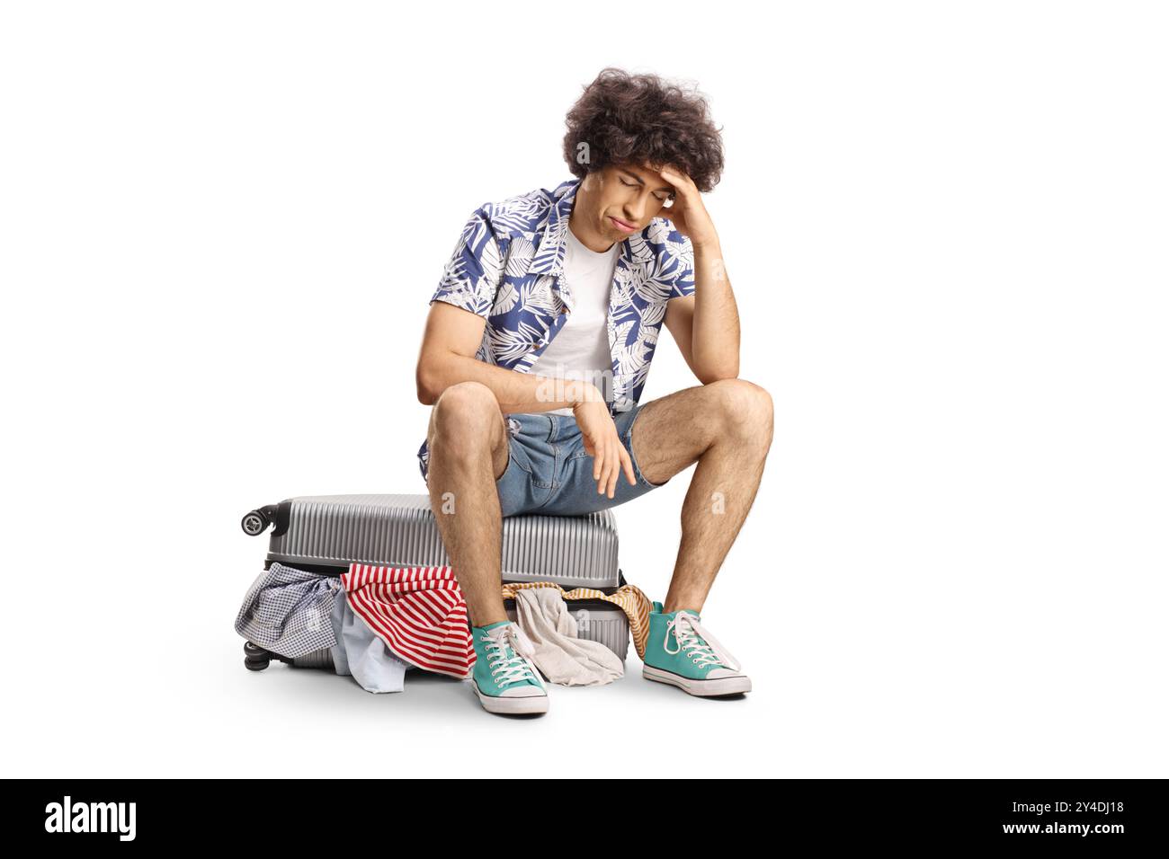 Trauriger junger Mann mit überfülltem Koffer, der isoliert auf weißem Hintergrund denkt Stockfoto