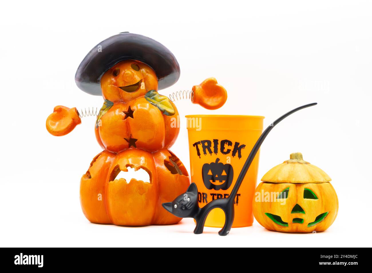 Halloween-Display mit einem Jack o Laterne, Kürbiskerzenhalter, kürbisförmigem Plastikbecher und einer schwarzen Katzenfigur auf weißem Hintergrund Stockfoto