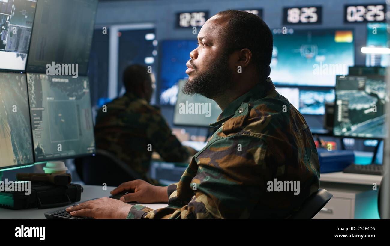 Armeeoperateur in der Kommandozentrale analysiert Überwachungsdaten während des globalen Krieges. Der Geheimdienstagent in der Basis der Operationen beendet die Mission während der geopolitischen Operation des 3. Weltkriegs, Kamera A Stockfoto