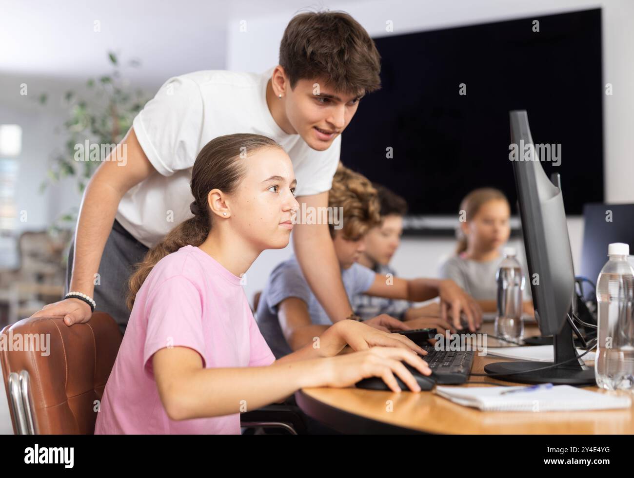Der Guy Teacher bringt Mädchen bei, wie man Computer benutzt Stockfoto