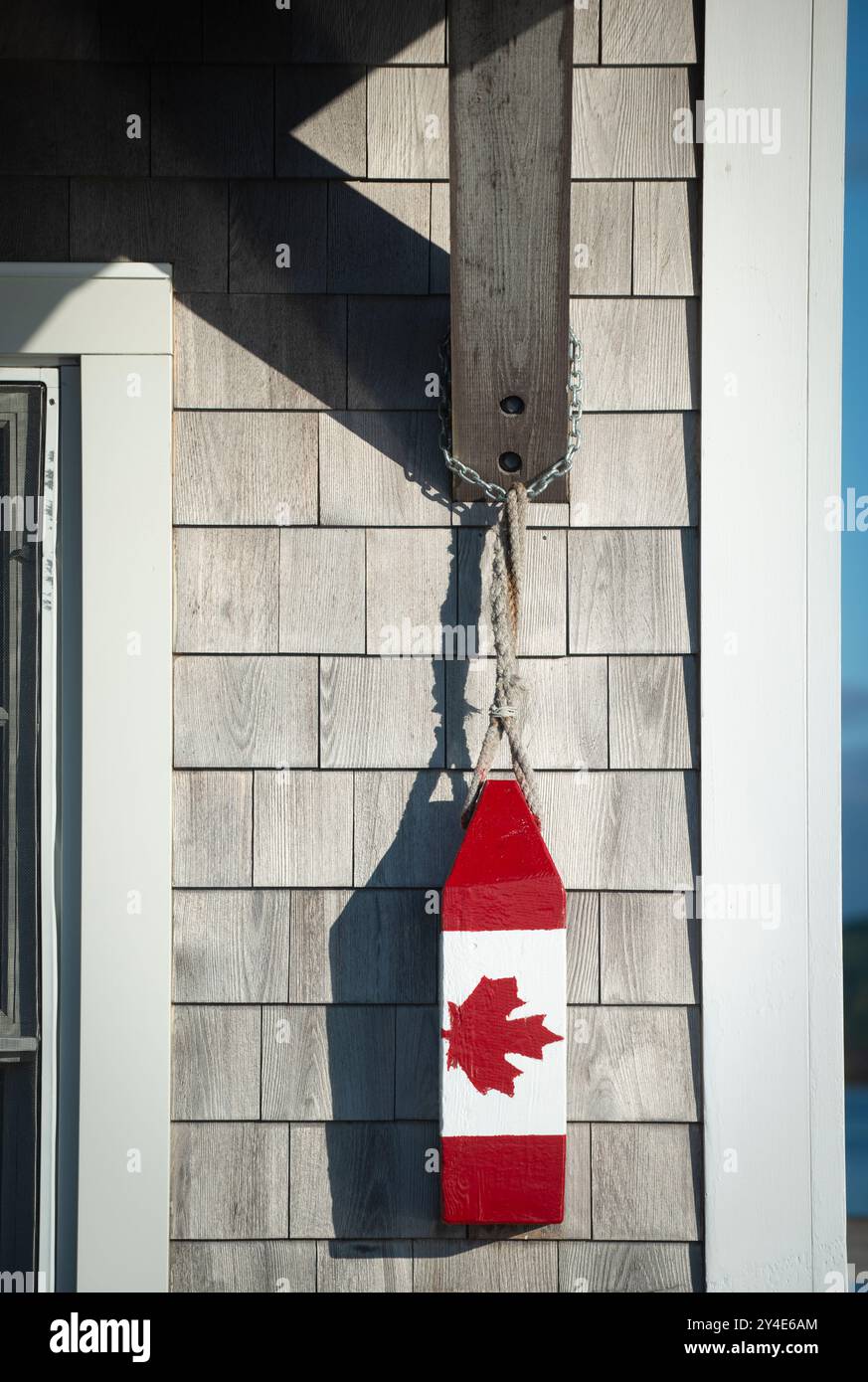 Vintage-Hummerboje rot-weiß mit dem roten kanadischen Ahornblatt, der kanadischen Flagge, hängt vor dem Büro des Hafenmeisters an der Market Wharf in der Passamaquoddy Bay im Zentrum von Saint Andrews, New Brunswick, Kanada. Stockfoto