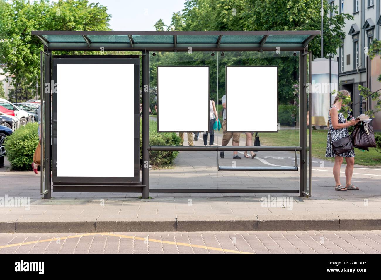 Drei leere vertikale Mockups von Reklametafeln an der Bushaltestelle vor Einem Stadtpark. Leere Weiße Werbeflächen Auf Dem Bürgersteig Stockfoto