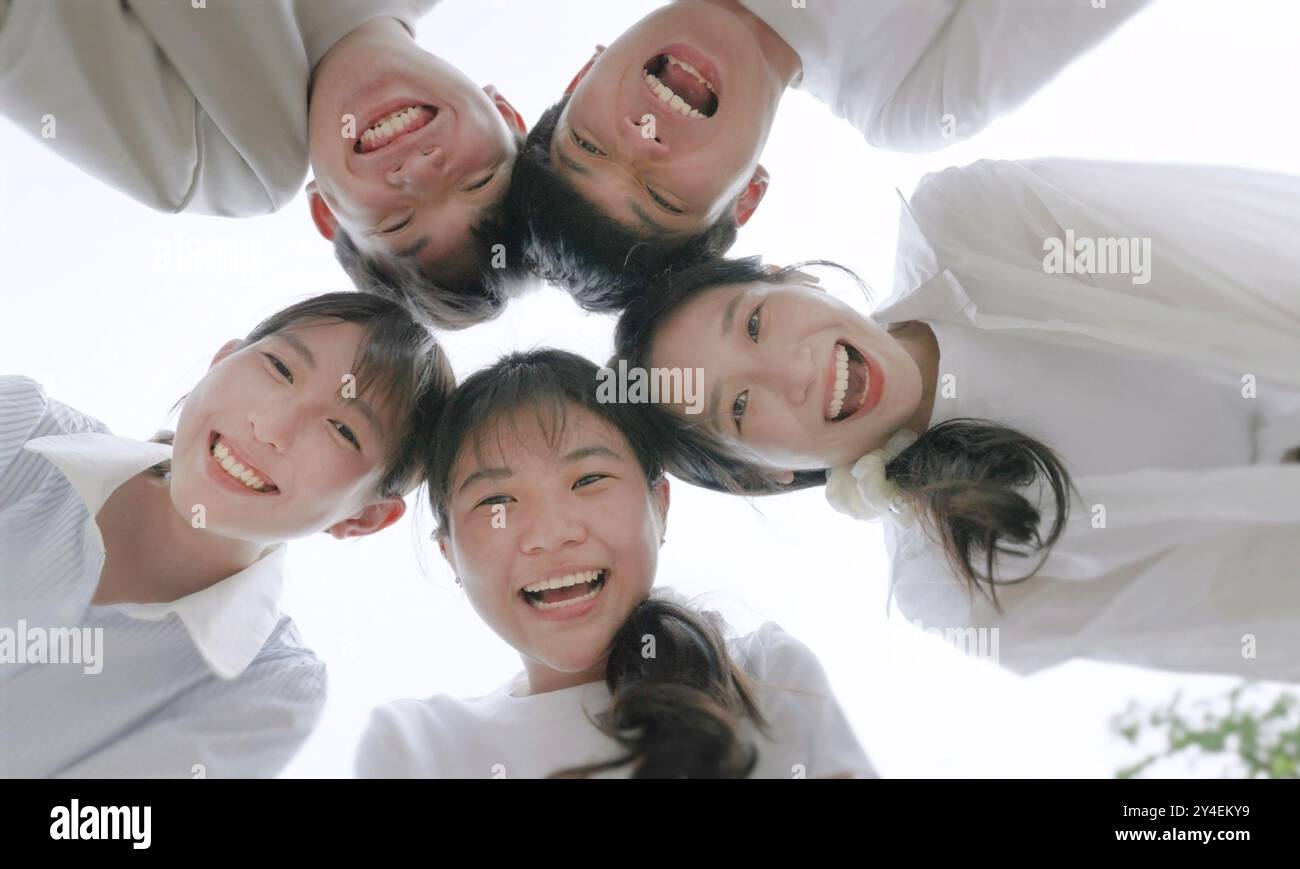 Junge, schöne Leute, die im Kreis stehen und vor der Kamera lächeln. Stockfoto