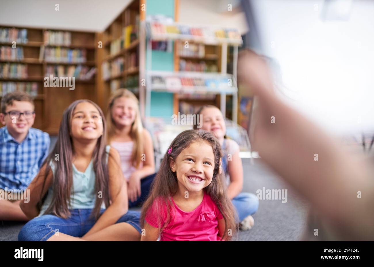 Glücklich, Schule und Lehrer lesen Kindern im Klassenzimmer vor, um Lektion, Lernen und Geschichte zu machen. Unterricht, Bücherei und Jungen und Mädchen hören zu Stockfoto