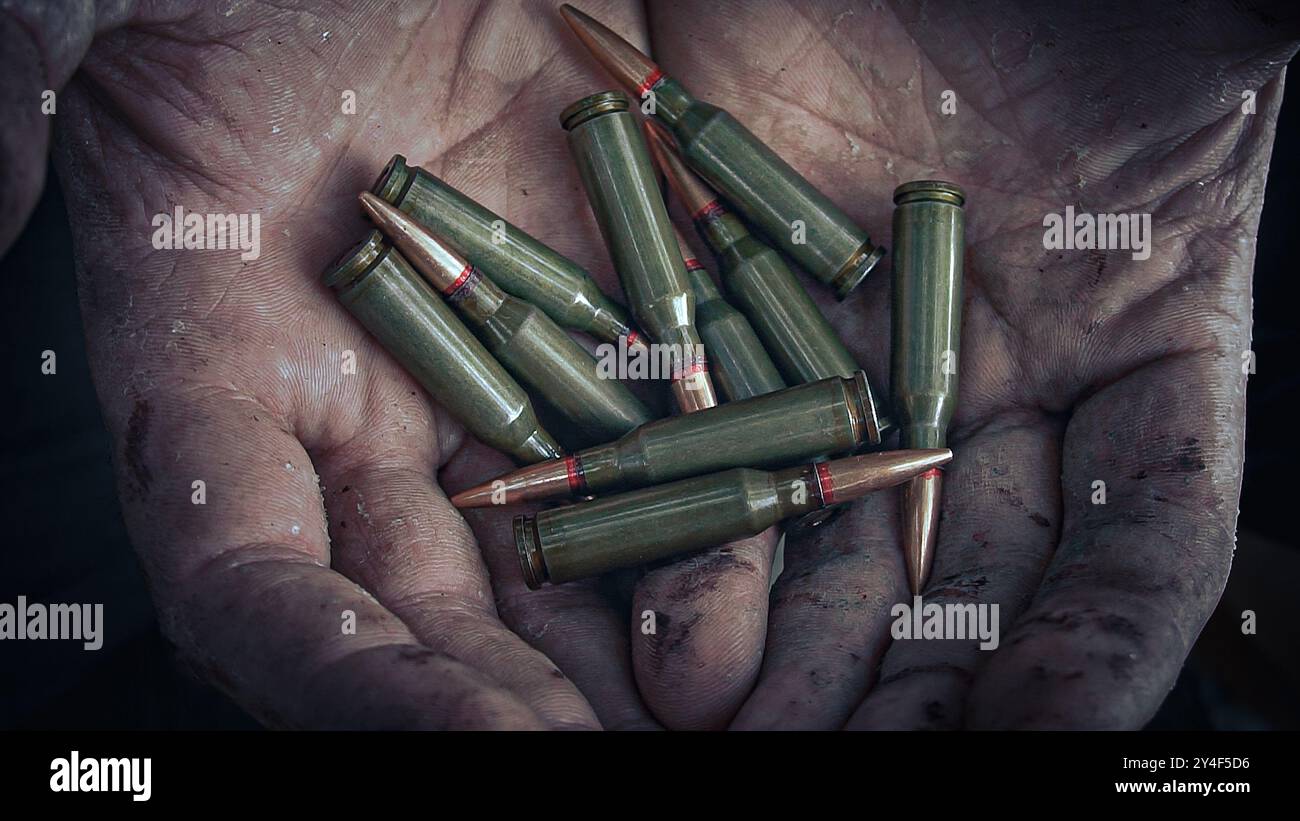 Der Soldat hält Patronen in seinen blutigen Händen. Stockfoto