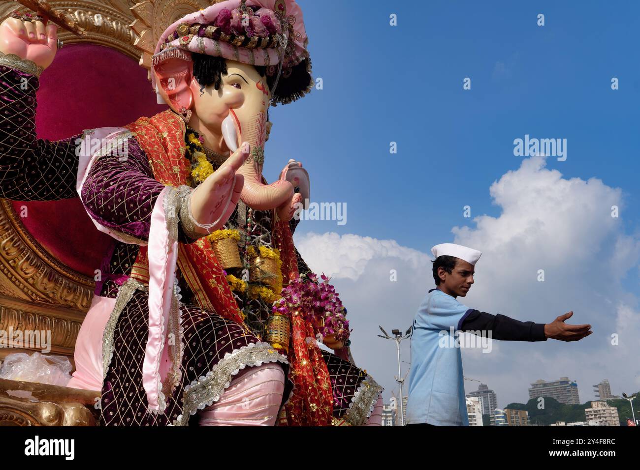 Ein Mann mit einem Maharashtrianischen Topi (Cap), während des jährlichen Ganesh Festivals, unter einer Figur des hinduistischen Elefantengottes Ganesh, Mumbai, Indien Stockfoto