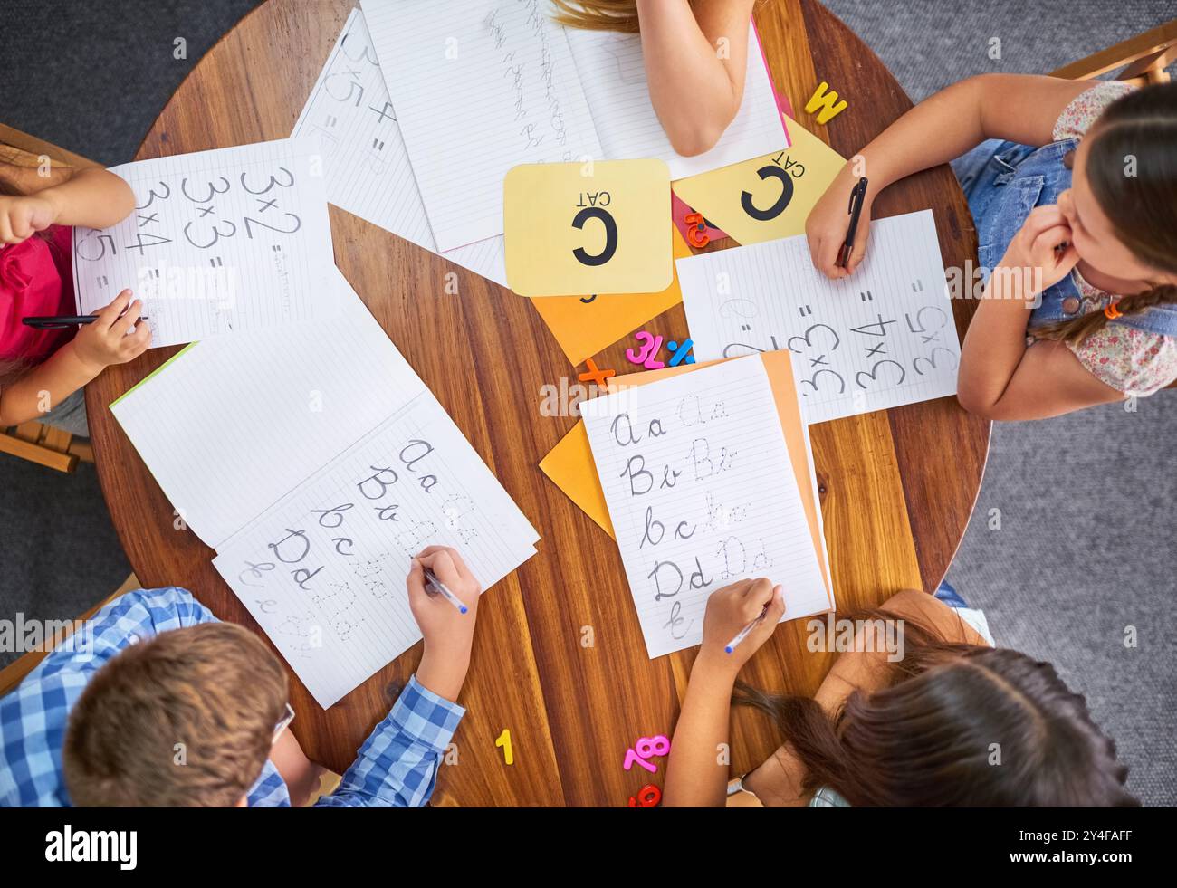 Bildung, Gruppe und Kinder, die in der Praxis schreiben lernen, Aktivität im Klassenzimmer in der Schule. Leute, über und Kinder Schüler mit Büchern und Flash-Karten Stockfoto