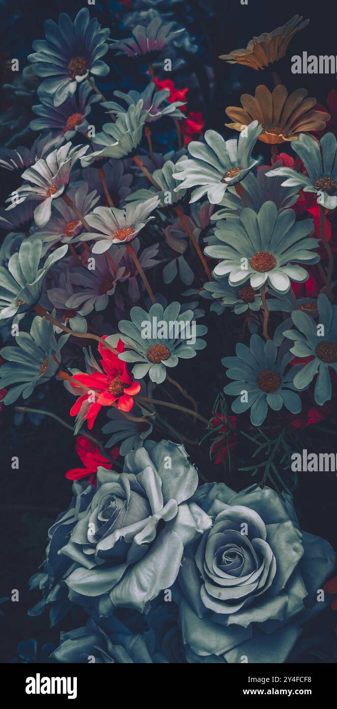 Eine Nahaufnahme eines Vintage-Blumenstraußes aus künstlichen Blumen in gedämpften Tönen, mit einem Schwerpunkt auf blauen und grauen Blumen. Stockfoto