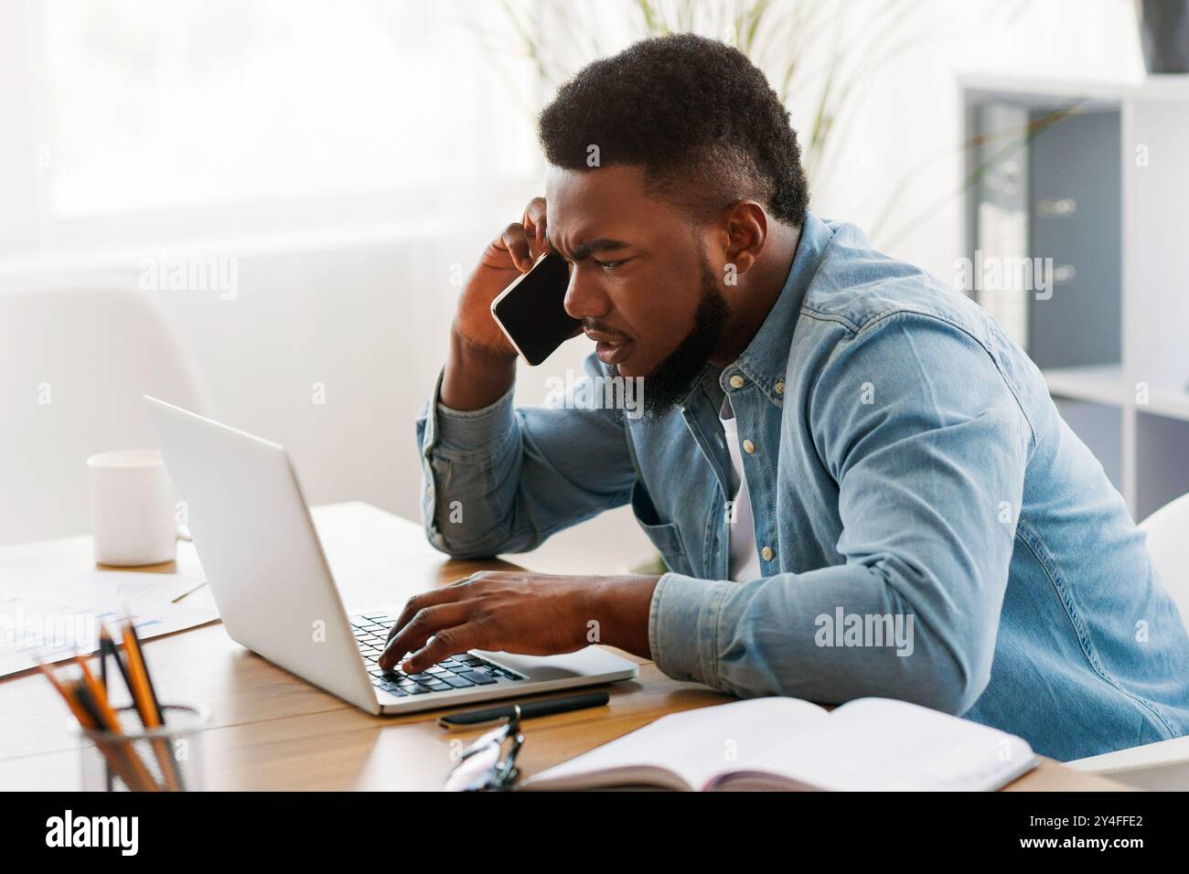 Besorgt Geschäftsmann mit Mobiltelefon und Laptop Bildschirm Stockfoto