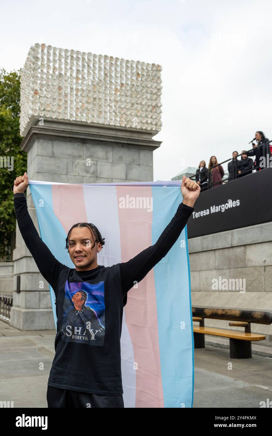 London, Großbritannien. 18. September 2024. Ein Mitglied der Trans-Gemeinschaft mit einer Trans-Flagge bei der Enthüllung von „MIL Veces un Instante (A Thousand Times in an Instant)“ durch Teresa Margolles, die Vierte sockelkommission am Trafalgar Square. Das Werk ist eine Hommage an die transkurrile und nicht-binäre Gemeinschaft in Margolles’ Heimatland Mexiko und zeigt weiße Gipsabgüsse, wie Todesmasken, aber aus den Gesichtern von 726 lebenden Trans-Menschen in Mexiko, die auf dem Sockel angeordnet sind. Das Kunstwerk basiert auf Margolles’ Leben, bevor sie als forensische Pathologin zur Künstlerin wurde. Quelle: Stephen Chung / Alamy Live Stockfoto