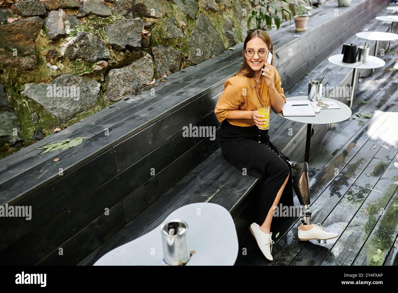 Eine junge Frau führt ein lebhaftes Telefongespräch, während sie in einem Café einen erfrischenden Drink schlürft. Stockfoto